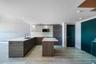 Kitchen featuring wood-finish cabinetry, an island with a light-toned countertop, undermount sink, built-in microwave, and tile flooring