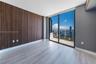 Wood-slat accent wall, tile flooring, floor-to-ceiling glass sliding doors, and private balcony with water and city skyline
