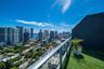 Balcony featuring synthetic turf flooring, metal and glass railing, and urban skyline backdrop