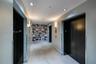 Elevator lobby featuring two matte black elevator doors, large-format tile flooring, recessed ceiling lighting, and a geometric-patterned accent wall
