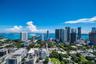 Aerial perspective featuring a metropolitan skyline, coastal waterway, bridge infrastructure, and dense urban greenery