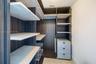 Custom walk-in closet featuring dark wood-finish cabinetry, light-toned open shelving, integrated three-drawer dresser unit, and wire storage racks