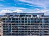 High-rise structure featuring floor-to-ceiling glass windows, expansive private balconies with glass railings, and a roof-level deck