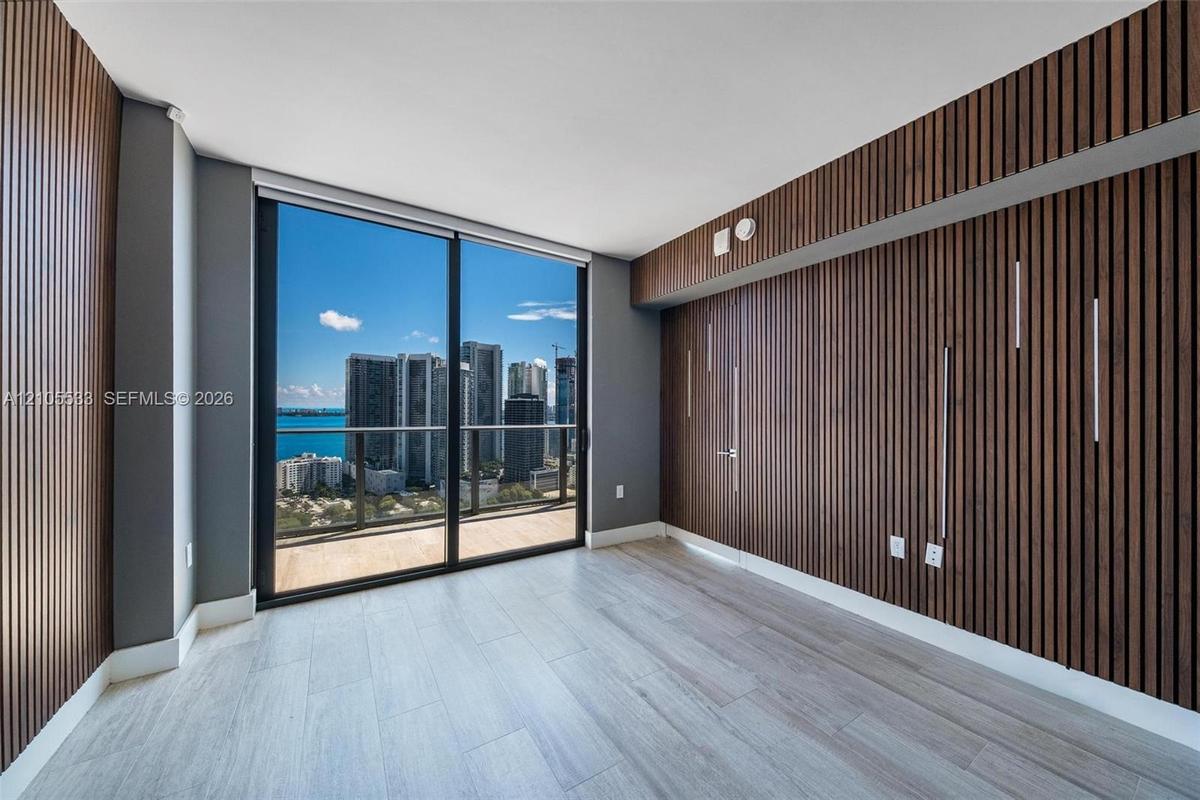 Floor-to-ceiling windows, wood-slat accent walls, wood-finish flooring, and a private balcony