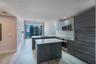 Modern kitchen featuring wood-finish cabinetry, quartz countertops, a kitchen island, stainless steel built-in appliances, and tile flooring