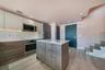 Kitchen featuring flat-panel cabinetry, a central island with a solid-surface countertop, stainless steel appliances, wood-finish flooring, and a glas