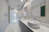 Double vanity featuring wood-finish cabinetry, white countertop, vessel sinks, chrome fixtures, and wall-mounted rectangular mirrors