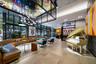 Expansive lobby featuring floor-to-ceiling windows, large-format tile flooring, industrial-style grid ceiling structure with integrated lighting, and 