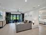 High-gloss black cabinetry, quartz countertops, wood-finish flooring, coffered ceiling with recessed lighting, and built-in stainless steel appliances