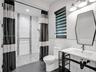 Floor-to-ceiling stone slab focal wall, two crystal-accented pendant light fixtures, and dual built-in side cabinets with stone tops