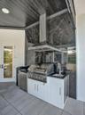 Wood-finish flooring, floor-to-ceiling black-framed windows, integrated wall-mounted headboard, and circular multi-tiered chandelier