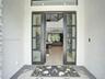 Modern pivot-style entry door featuring a matte black frame with floor-to-ceiling glass paneling and light-toned wood-finish flooring