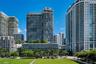 High-rise residential tower featuring glass facade construction, expansive private balconies, and landscaped podium-level terrace