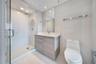 Bathroom featuring a glass-enclosed shower, light wood-finish vanity with a countertop basin, wall-mounted mirror, and tile flooring