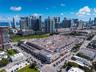 Aerial perspective of a multi-level commercial complex featuring integrated parking facilities, ground-level retail spaces, and a prominent corner arc