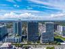 Aerial perspective of a high-rise urban landscape featuring glass-facade residential towers, expansive horizontal balconies, and incorporated podium-l