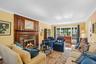 Spacious & sunfilled living room wih fireplace is framed on either end by floor to ceiling windows allowing beautiful views of the gardens