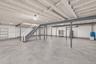 Unfinished basement with 9 ft ceilings. Open-concept lower level featuring exposed ceiling joists, concrete flooring, steel support beams, and painted