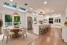 Kitchen featuring white cabinetry, center island with stone-finish countertops, stainless steel appliances, recessed skylights, and wood-finish floori