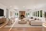 Living area featuring wood-finish flooring, a tray ceiling, recessed lighting, expansive multi-pane windows, and a floor-to-ceiling stone fireplace