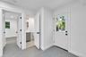 Neutral-toned ceramic tile flooring, solid-core shaker style interior doors with matte black hardware, and an exterior door with a nine-pane window in