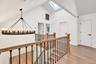Vaulted ceiling with skylight, wood-finish flooring, and chandelier featuring a circular metal frame with tiered candelabra bulbs