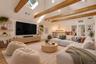 2nd floor loft. Vaulted ceiling with exposed wood beams, skylights, built-in wall shelving, wood-finish flooring, and a multi-light chandelier