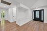 Entryway featuring wood-finish flooring, a built-in recessed display niche with a solid surface bench, vaulted ceiling, and a black-framed front door 