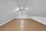 Attic space featuring vaulted ceilings, recessed lighting, wood-finish flooring, and a central window