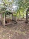 ...outdoor space featuring a wood-framed pergola with lattice sides, a suspended bench...