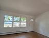 Interior space featuring expansive triple-pane windows, cathedral ceiling, wood floors, and a white entry door with a decorative glass insert.