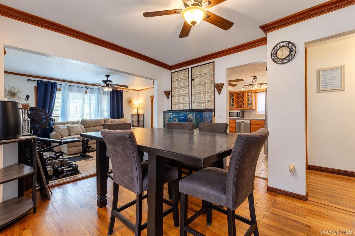 Dining area featuring wood-finish flooring, crown molding, and a central ceiling fan with integrated lighting