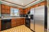 Kitchen featuring stained wood cabinetry, stainless steel refrigerator, patterned tile flooring, and a tiled backsplash