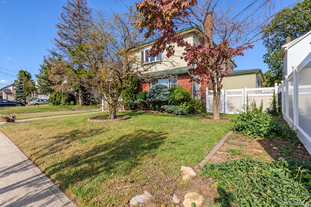 Two-story residence featuring a brick and siding exterior, a chimney, and a white privacy fence