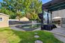 In-ground pool with stone paver surround, covered patio structure, and perimeter lattice fencing
