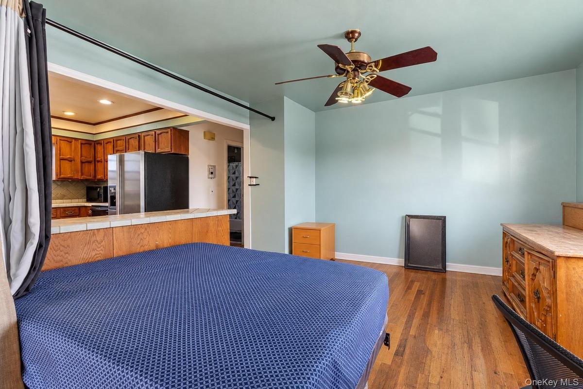 Wood-finish flooring, ceiling fan with integrated lighting, tiled breakfast bar, and kitchen cabinetry