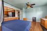 Wood-finish flooring, ceiling fan with integrated lighting, tiled breakfast bar, and kitchen cabinetry
