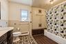 Bathroom featuring a dark wood vanity with an integrated basin, patterned tile flooring, a bathtub surround with decorative tile accents, and a textur