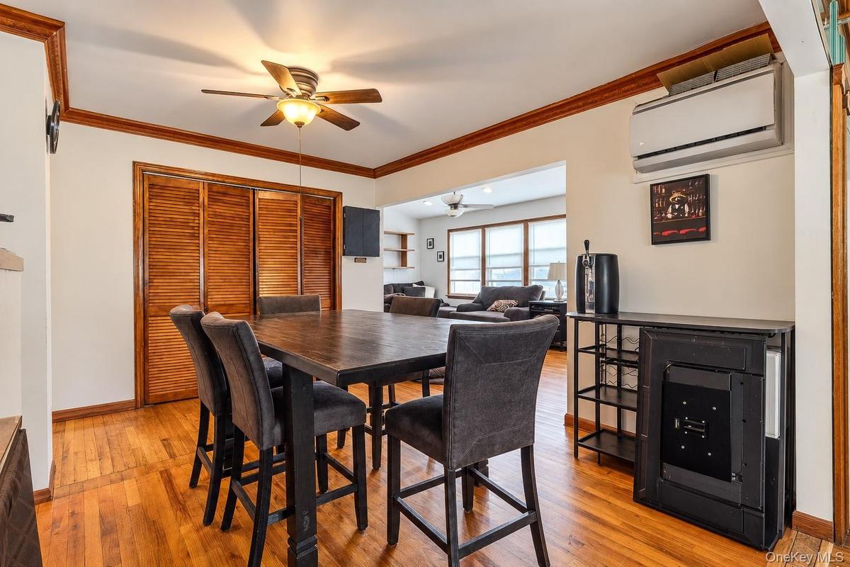 Wood-finish flooring, crown molding, louvered-panel closet doors, and a wall-mounted ductless air conditioning unit