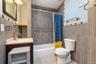 Bathroom featuring stone-finish wall tiling with mosaic accents, a built-in vanity with a stone countertop, an integrated oval sink, and a combination