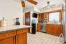 Kitchen featuring tile-topped cabinetry, stainless steel dishwasher, wood-finish cabinetry with integrated wine storage, hexagonal tile flooring, and 