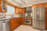 Kitchen featuring custom wood cabinetry, stainless steel appliances, a modern chimney-style range hood, hexagonal tile flooring, and a decorative tile
