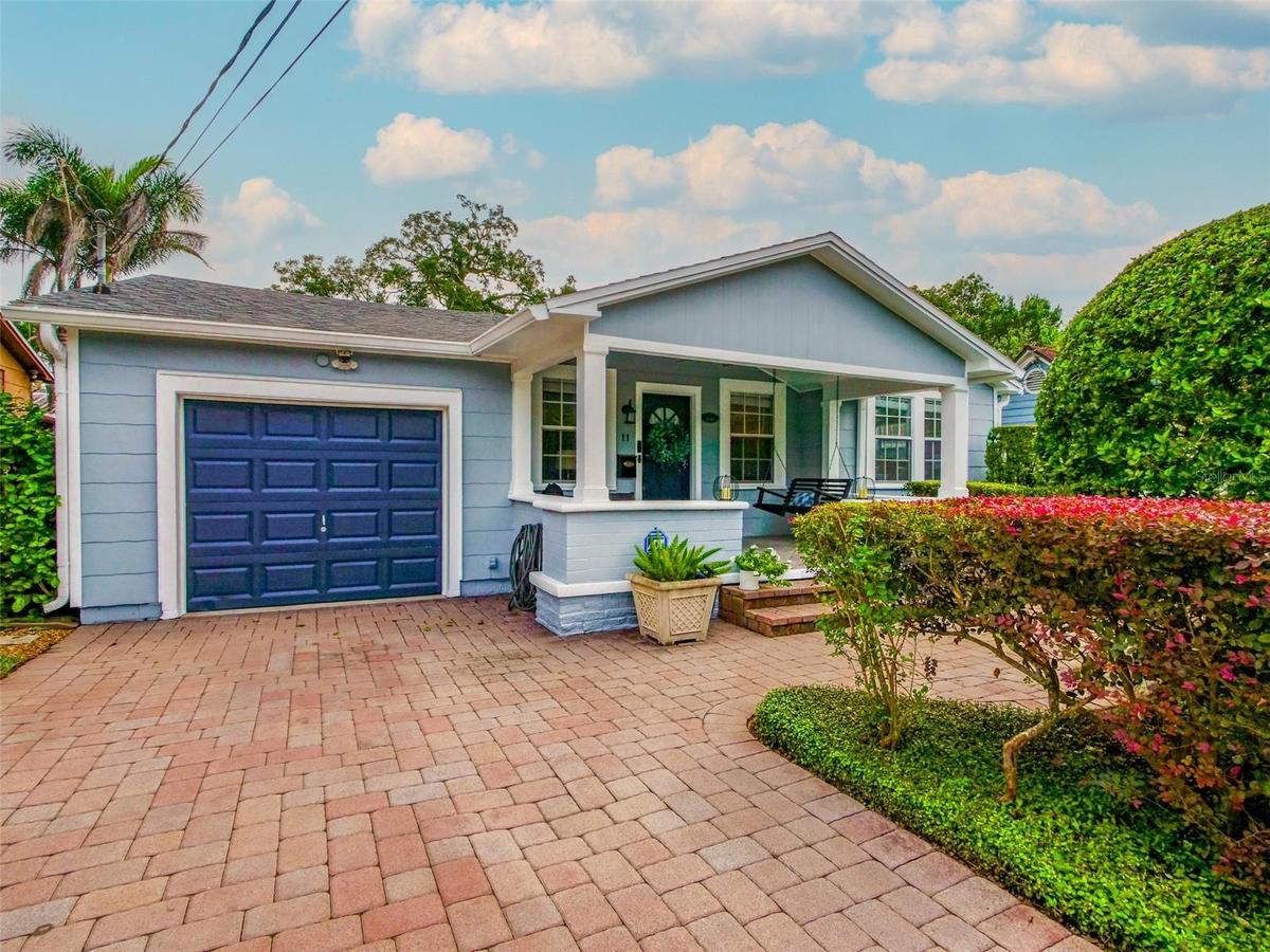 Front exterior with paver driveway, covered front porch, and attached garage