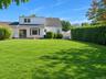 Expansive rear lawn with mature privacy hedging and established landscaping