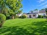 Expansive rear lawn with mature trees and established perimeter hedges
