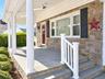 Covered front porch with skylights, stone facade, columns, bluestone stair and flooring, and a white railing with square balusters