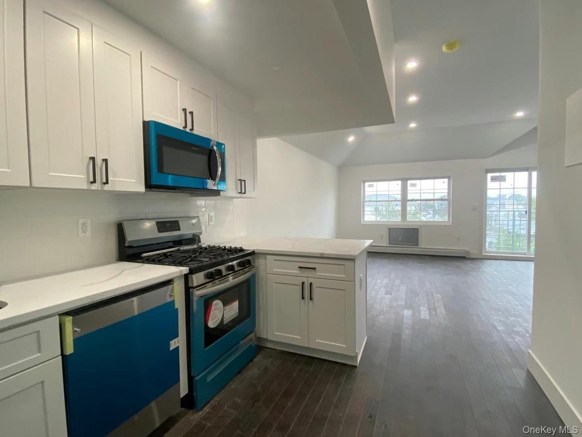 Kitchen with dark hardwood / wood-style flooring, white cabinets, and stainless steel appliances