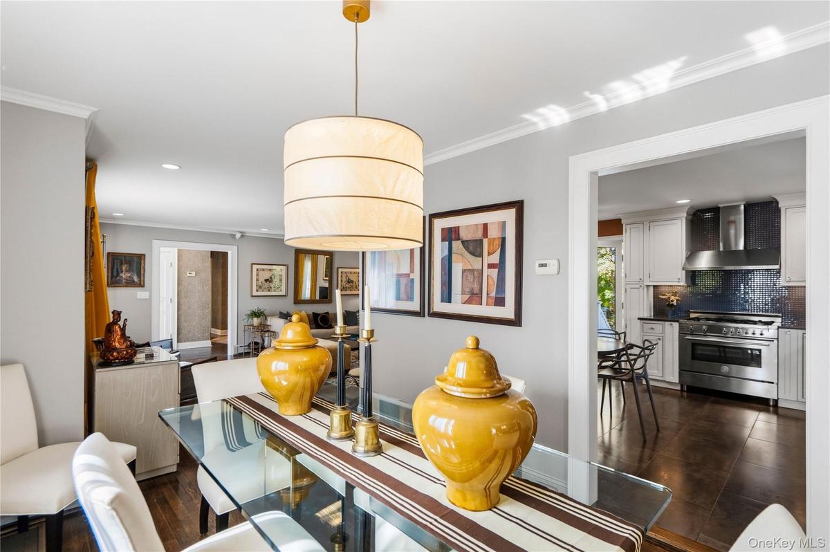 Neutral-toned interior featuring hardwood flooring, a cylindrical pendant light fixture, crown molding, and recessed lighting
