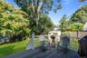 Elevated deck Trex deck featuring Azak railings, a manicured lawn,  fenced backyard, and mature trees