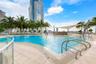 Resort-style pool with integrated steps, surrounding tile decking, and a contemporary shade structure